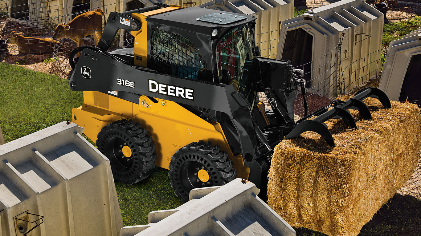 John Deere Skid Steer with Scrap Grapple Attachments hauling straw.